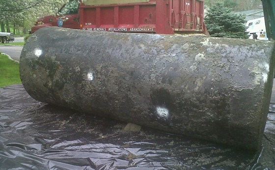 1000 gallon leaking tank on poly in yard with marked holes